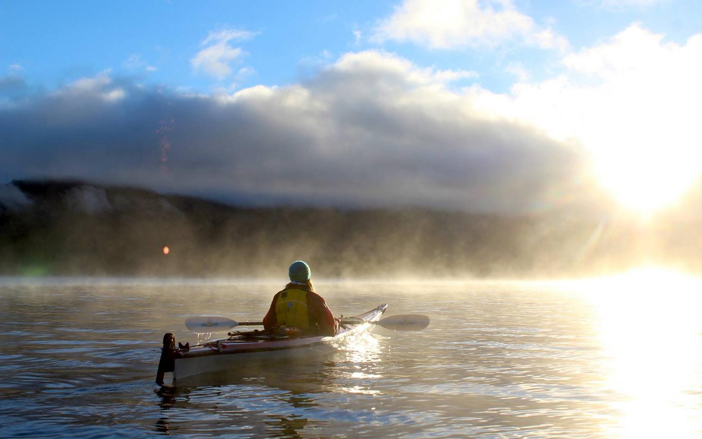 person in kayak on the water at sunrise